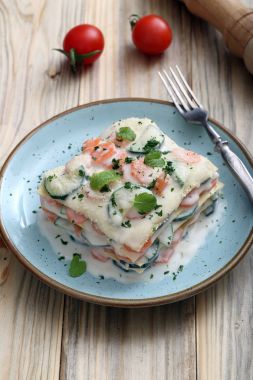 Vejetaryen lazanya ile dilimlenmiş havuç, kabak ve parmesan hizmet üzerinde mavi tabak çatal ile sos
