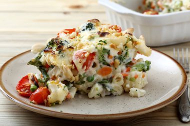 Sebze ve ahşap masa üzerinde beyaz tabakta servis peynir pişmiş makarna