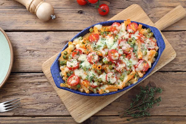 焼きたてのリガトーニ トマト エンドウ豆とチーズの木の板に青色のセラミック皿で提供しています — ストック写真