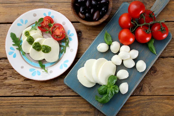 素朴なテーブルの上にトマトとバジルと伝統的なイタリアのモッツァレラ — ストック写真