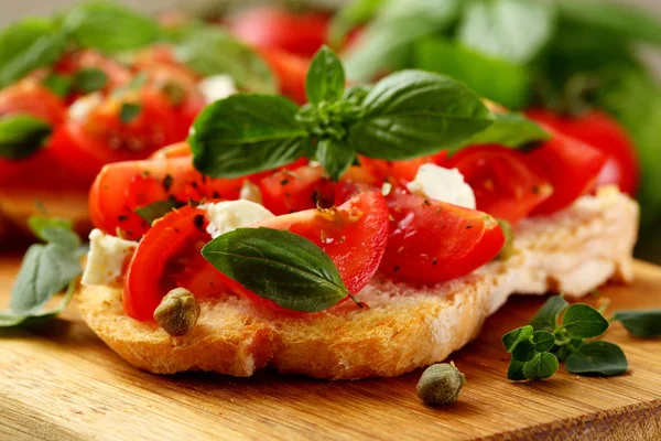 Brottoasts Mit Tomaten Knoblauch Und Kapern Mit Basilikum Auf Rustikalem lizenzfreie Stockfotos
