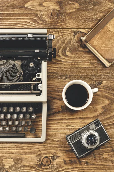 Vintage typewriter, cup of coffee,camera and a notebook on wooden table