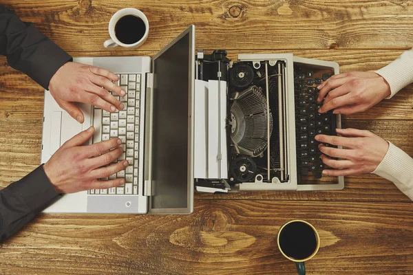 Mulher escrevendo em uma máquina de escrever e um homem trabalhando em um laptop.Clos — Fotografia de Stock