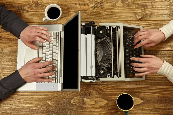 Mulher escrevendo em uma máquina de escrever e um homem trabalhando em um laptop.Clos — Fotografia de Stock