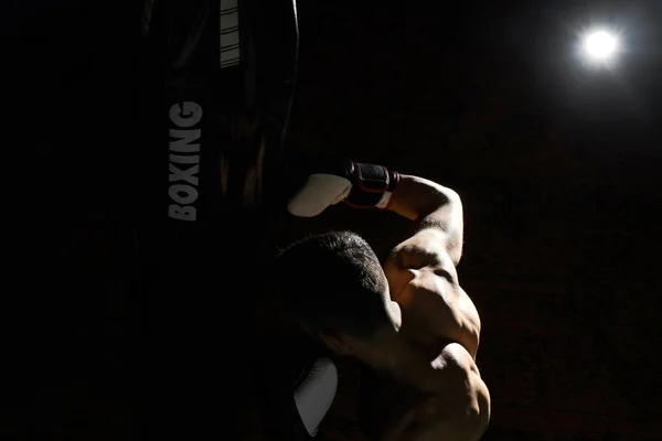 Entrenamiento de boxeador de patadas en un gimnasio con saco de boxeo . —  Fotos de Stock