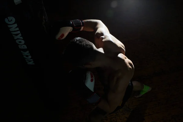 Entrenamiento de boxeador de patadas en un gimnasio con saco de boxeo . — Foto de Stock