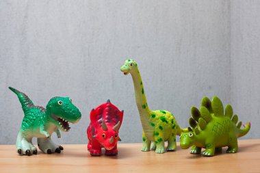 Ahşap bir zemin üzerinde duran dört dinozorlar oyuncaklar.