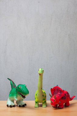 Ahşap bir zemin üzerinde duran üç dinozorlar oyuncaklar.