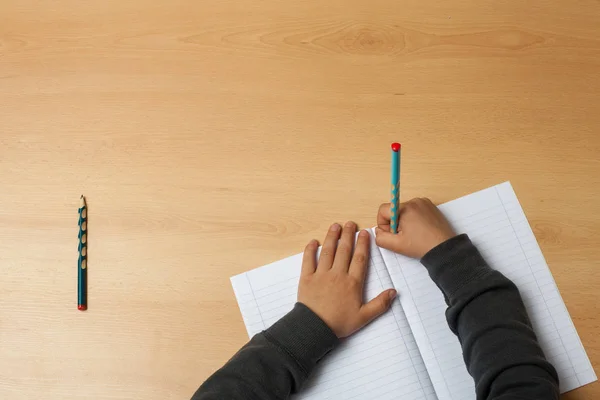 Çocuk bir defter üzerinde yazıyor.