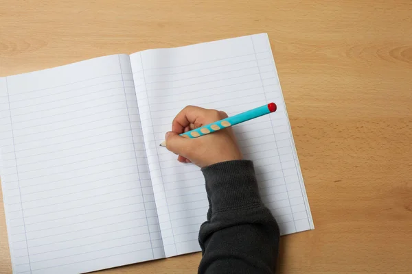 Çocuk bir defter üzerinde yazıyor.