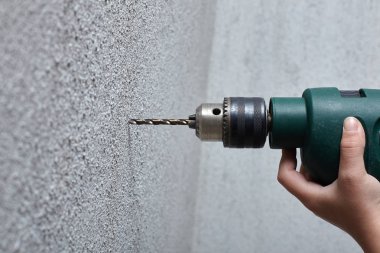 Worker drilling a hole into the wall with an electric drill. clipart