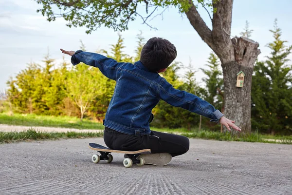 Kid Skater siedzi na swojej deskorolce i czuje się szczęśliwy. — Zdjęcie stockowe