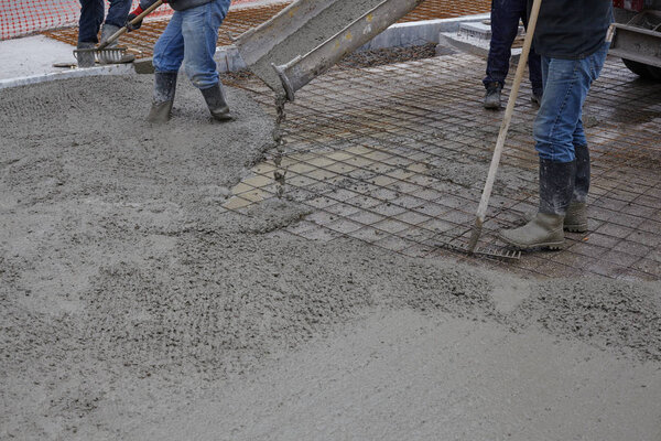 workers pouring wet concrete using concrete bucket. Industrial c