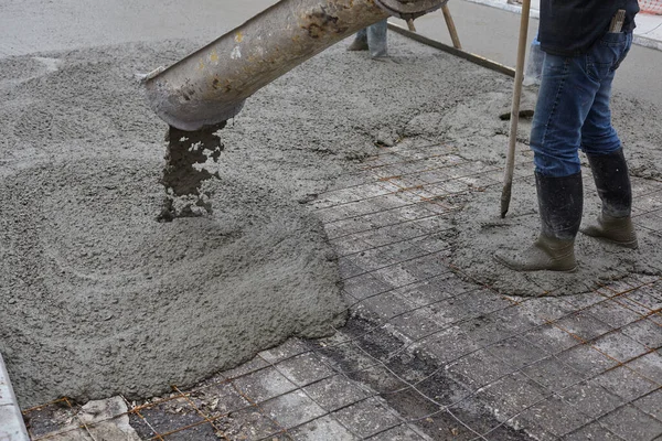 Lavoratori versando cemento bagnato con secchio di cemento. Settore industriale Immagine Stock