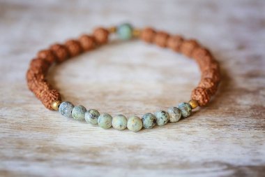 Doğal mineral taşı, doğal ahşap arka planda yoga bileziği takar.