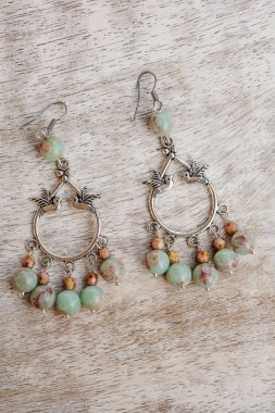 Boho metali doğal mineral taşından küpelerle tarafsız ahşap arka planda.