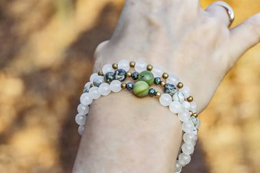 Orman arka planında kadın eli üzerinde mineral taş bilezik.