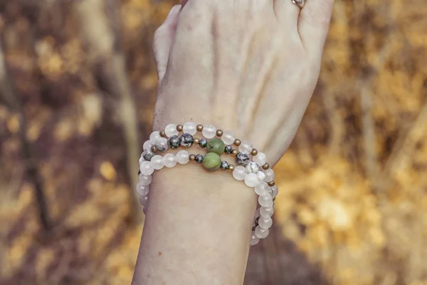 Mineral stone bracelet on female hand detail in forest background