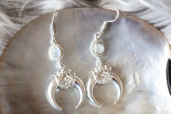 White metal earrings in the shape of the moon with moon stone gemstone