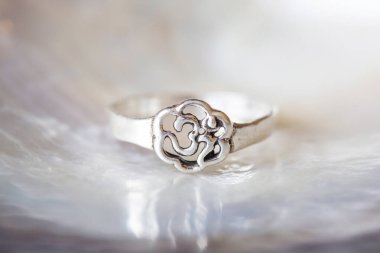 Gümüş yüzük, beyaz inci arkaplanlı, om şeklinde küçük mücevher parçası.