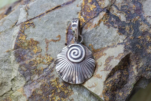 sterling silver metal pendant on natural background in the shape of the shell