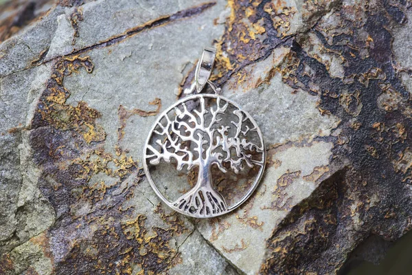 sterling silver metal pendant on natural background in the shape of the tree