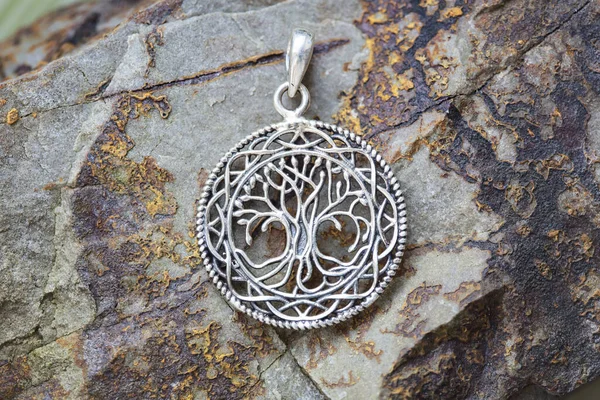 sterling silver metal pendant on natural background in the shape of the tree