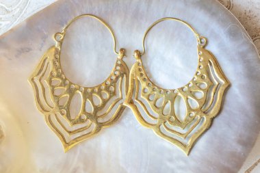 Beyaz kabuklu doğu lotusu şeklinde pirinç metal küpeler doğal arka plan