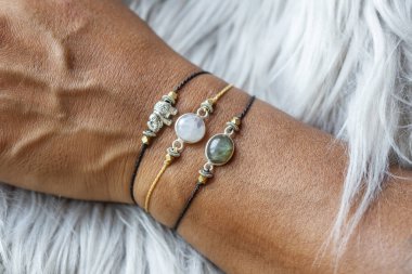 Öfkeli arka planda mineral taş bilezikler takan bir elin yakın çekimi. 