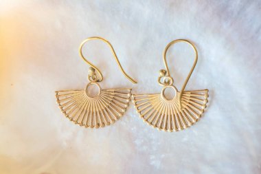 Beyaz kabuklu, zarif küpelerden oluşan pirinç metal bir çift.