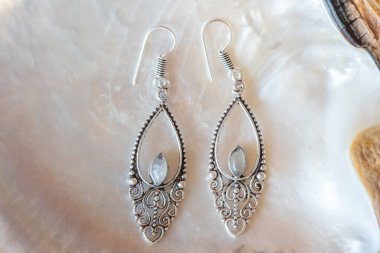 Beyaz kabuklu, zarif küpelerden oluşan pirinç metal bir çift.