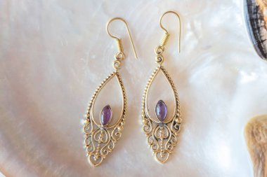 Beyaz kabuklu, zarif küpelerden oluşan pirinç metal bir çift.