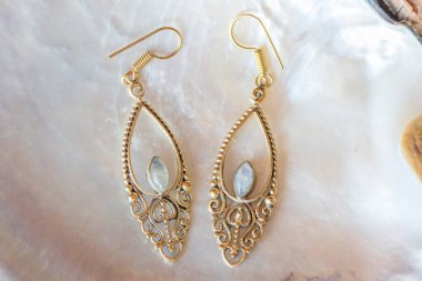 Beyaz kabuklu, zarif küpelerden oluşan pirinç metal bir çift.