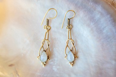 Beyaz kabuklu, zarif küpelerden oluşan pirinç metal bir çift.