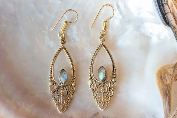 Beyaz kabuklu, zarif küpelerden oluşan pirinç metal bir çift.