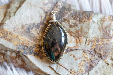 Kayalık arka planda doğal değerli taşlı pirinç kolye