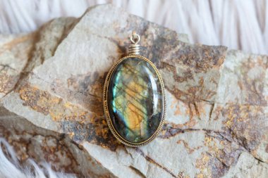 Kayalık arka planda doğal labradorit değerli taşı olan pirinç kolye.