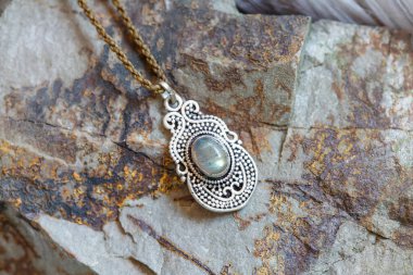 Kayalık arka planda doğal labradorit değerli taşı olan pirinç kolye.