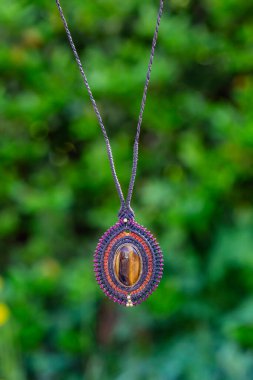 Doğal yeşil bokeh arka planında Macrame mineral taş kolye