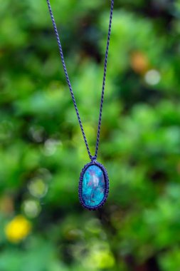 Doğal yeşil bokeh arka planında Macrame mineral taş kolye