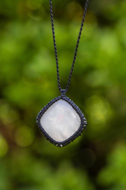 Doğal yeşil bokeh arka planında Macrame mineral kristal kuvars taşı kolye