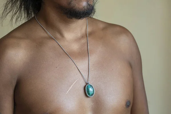 Male chest wearing elegant necklace with natural mineral gemstone