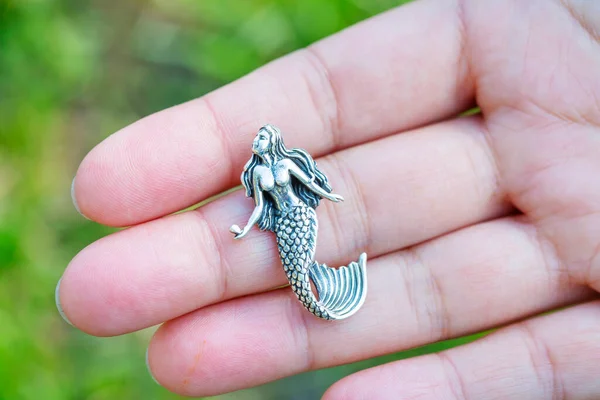 Sterling silver pendant in the shape of mermaid on female hand