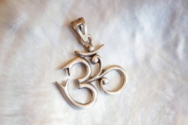 Beyaz kabuk arka planında om şeklinde Sterling siver kolyesi