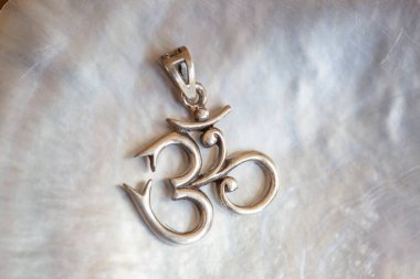 Beyaz kabuk arka planında om şeklinde Sterling siver kolyesi