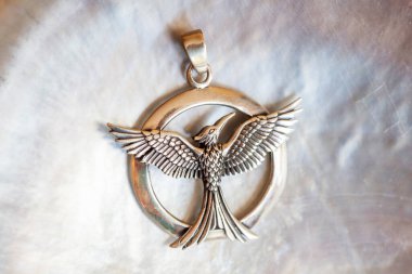 Sterling siver pendant in the shape of phoenix on white shell background clipart
