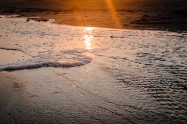 Sahilde bir gelgit havuzu üzerinden günbatımı
