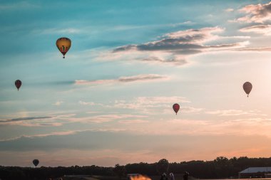 Sıcak hava balonları gün batımında havada süzülüyor.