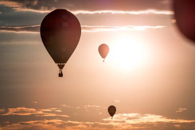 Sıcak hava balonları bir hava gösterisinde gün batımında havada süzülüyor.