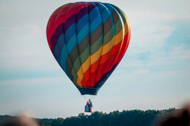 Gökkuşağı sıcak hava balonu gün batımında gökyüzünde uçuyor.